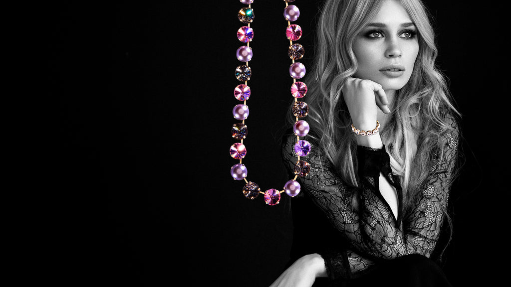 black and white elegant blonde woman wearing custom-designed jewelry from Cristal Jewelry, fuchsia, light rose stones, black patina necklace, clear crystal bracelet